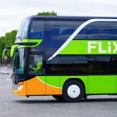 Dwupiętrowy autobus FlixBus z charakterystycznym zielonym logo. Kierowca w żółtej kamizelce. Czy FlixBus robi postoje? Tak, ten autobus jest w ruchu, prawdopodobnie na trasie.