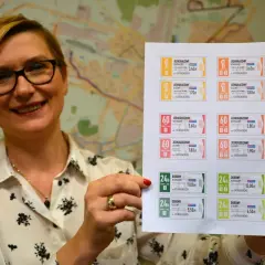 Kobieta prezentuje wydrukowane bilety ZTM Kielce. Na kartce widać różne rodzaje biletów jednorazowych i dobowych, z podanym cennikiem.