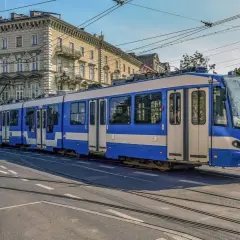 Kraków: Niebiesko-biały tramwaj na tle kamienicy, idealny środek transportu na weekendowy bilet rodzinny.