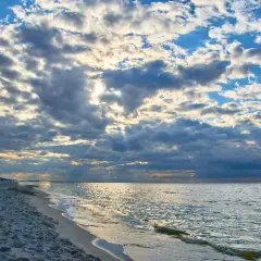 Piękny zachód słońca nad morzem. Chmury na niebie, piaszczysta plaża i spokojne fale. Stegna ile do morza? Niedaleko!
