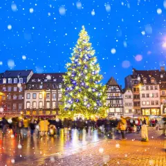 Magiczny, ośnieżony wieczór na jarmarkach bożonarodzeniowych w Europie. Rozświetlona choinka i tłumy ludzi tworzą świąteczną atmosferę.