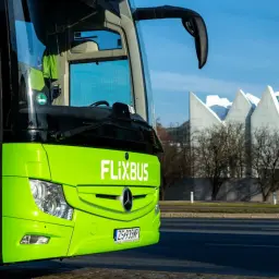 Zielony Flixbus czeka na pasażerów przy dworcu Młociny. W tle nowoczesna architektura.