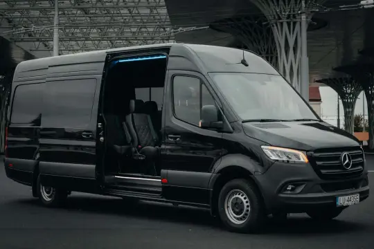 Czarny Mercedes Sprinter z otwartymi drzwiami, gotowy na przewozy do Belgii. Wygodne fotele i niebieskie oświetlenie wnętrza.