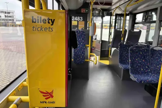 Wnętrze autobusu MPK-Łódź. Żółty automat z napisem "bilety tickets" i logo. Sprawdź cenę biletu na trasie Kutno-Łódź.