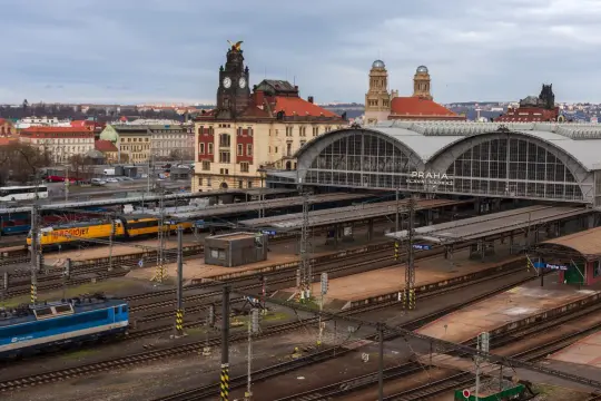 Pociąg do Czech czeka na dworcu Praha Hlavní Nádraží. Widać żółty pociąg RegioJet i niebieską lokomotywę.