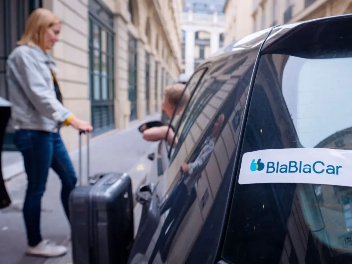 Kobieta z walizką wsiada do samochodu z logo BlaBlaCar. Tak działa wspólne podróżowanie.