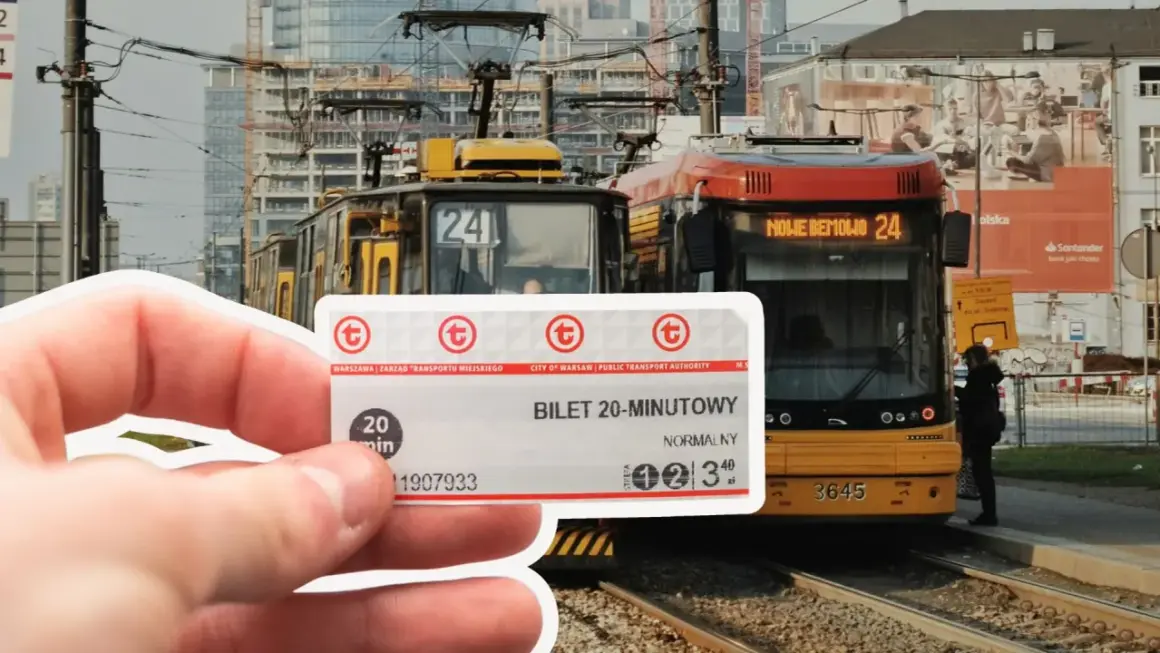 Warszawski bilet 20-minutowy w dłoni, na tle tramwajów i nowoczesnej zabudowy.