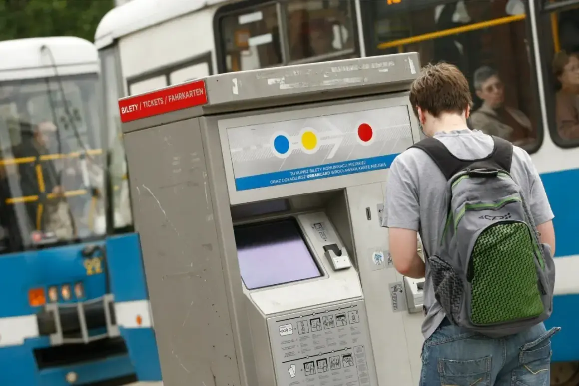 Młody mężczyzna z plecakiem kupuje bilet czasowy Wrocław na automacie przy niebieskim tramwaju.