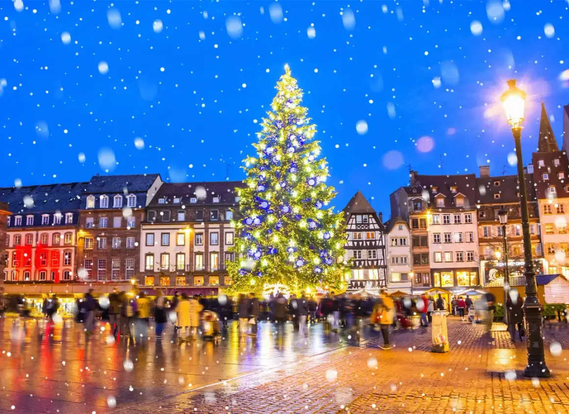 Magiczny, ośnieżony wieczór na jarmarkach bożonarodzeniowych w Europie. Rozświetlona choinka i tłumy ludzi tworzą świąteczną atmosferę.