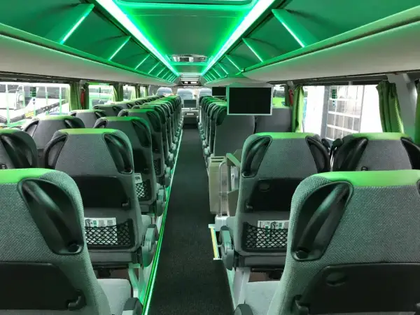 Wnętrze Flixbus autobusu z zielonym oświetleniem. Puste, wygodne siedzenia czekają na pasażerów.
