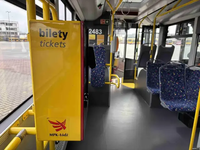 Wnętrze autobusu MPK-Łódź. Żółty automat z napisem "bilety tickets" i logo. Sprawdź cenę biletu na trasie Kutno-Łódź.